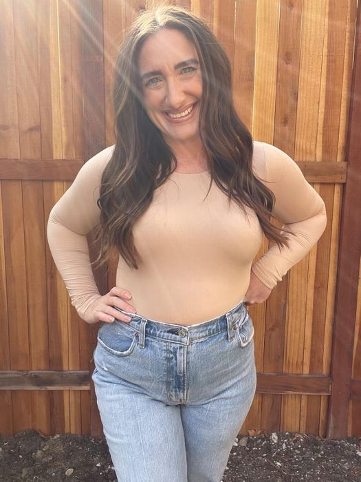 A reviewer posing in a nude-colored long-sleeve bodysuit.