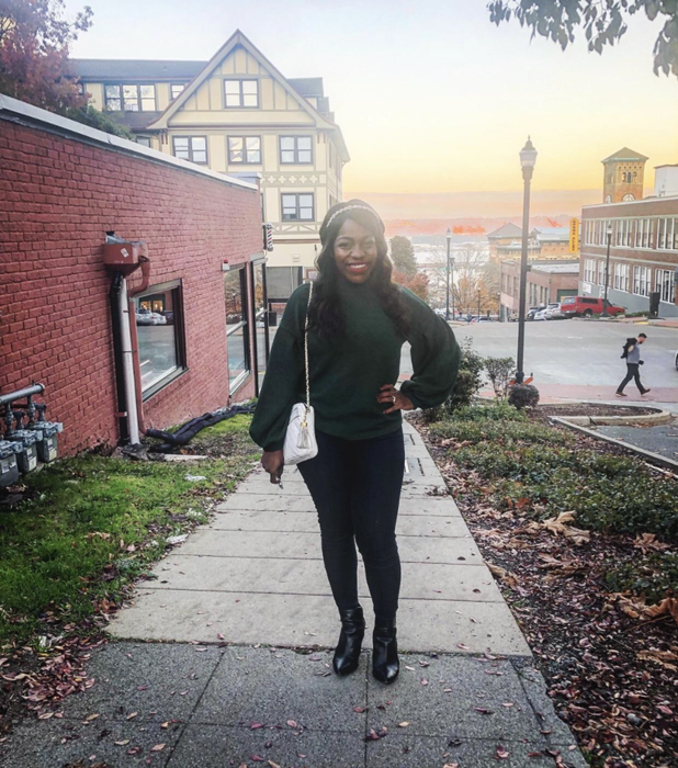 a reviewer modeling the sweater in a rich green shade