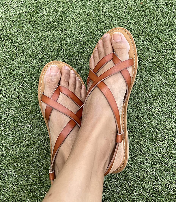 A reviewer wearing tan sandals while standing on grass