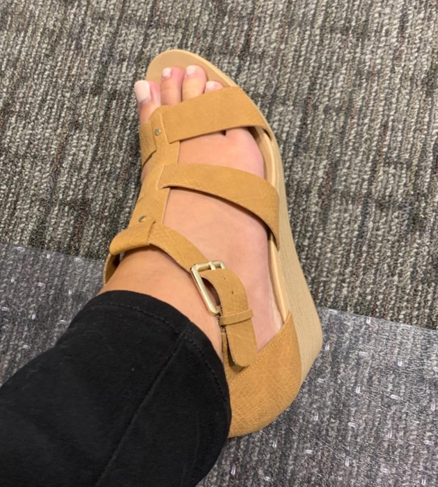 A reviewer wearing light brown sandals