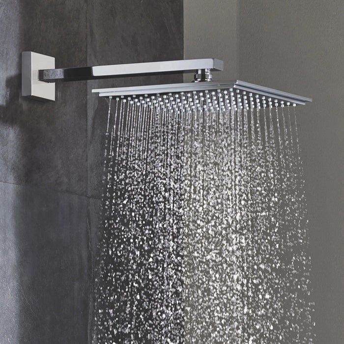 The square-shaped shower head releasing water in a shower