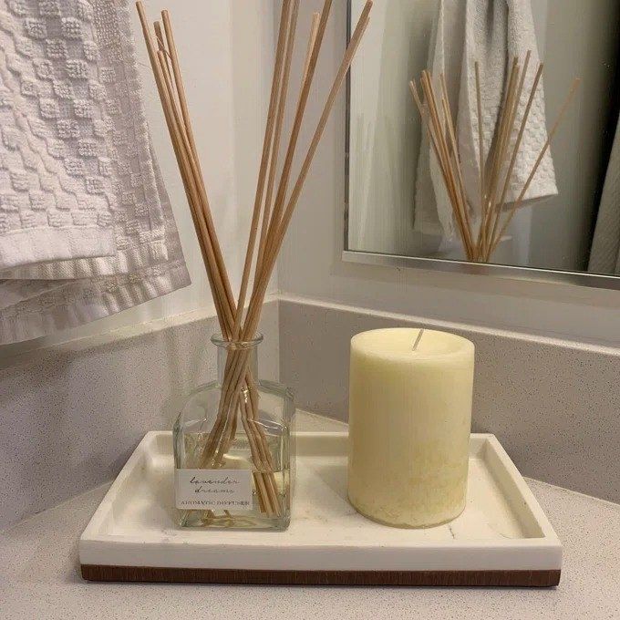 A diffuser, surrounded by several reeds, resting on a bathroom counter, adding a relaxing touch.