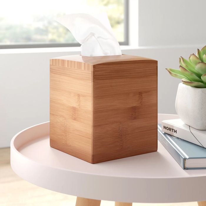 A tissue box holder elegantly covering a box of tissues, placed neatly on a table.