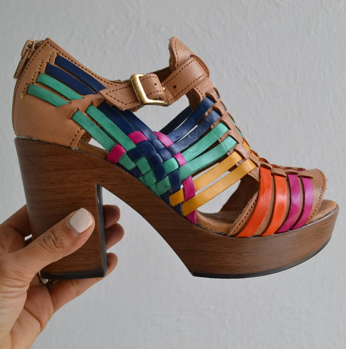 A reviewer holding a pair of multicolored platform sandals