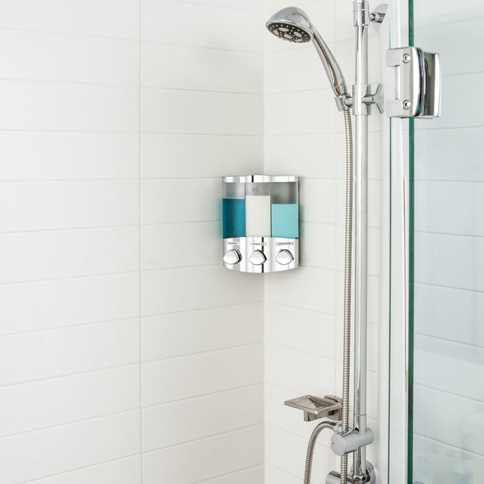 A mounted soap dispenser with three separate compartments installed on the wall of a shower, keeping everything tidy and easily accessible.
