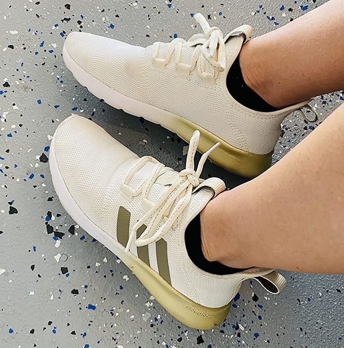 A reviewer showcasing the off-white sneakers featuring gold accents.