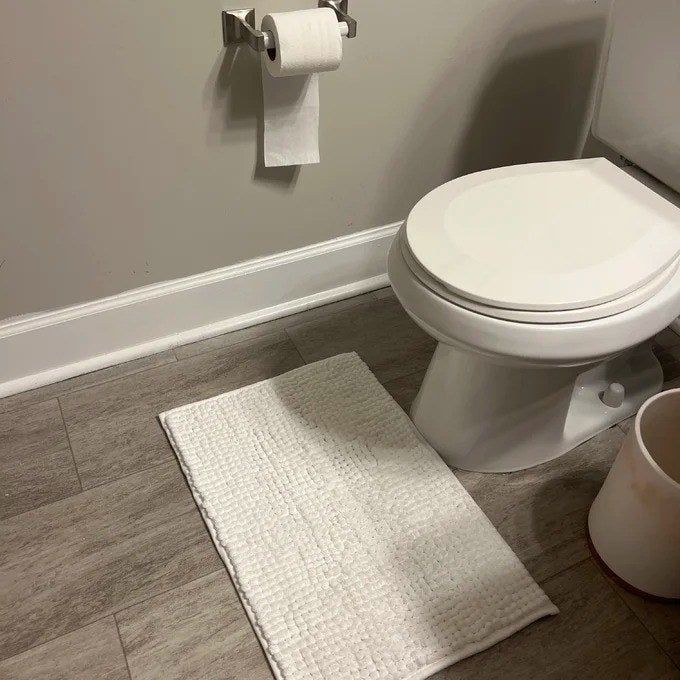 A photo shared by a reviewer showing a small mat placed underneath a toilet, adding both practicality and style to the bathroom.