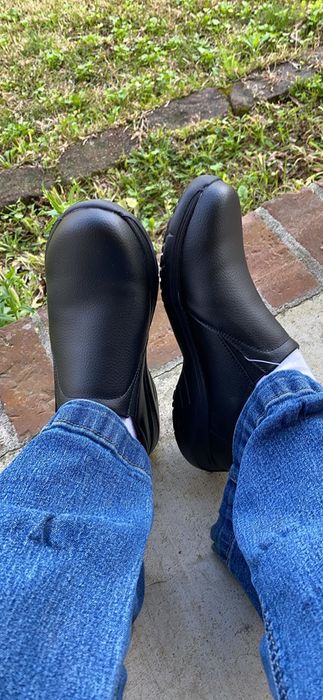 Reviewer seated outdoors in black shoes paired with jeans