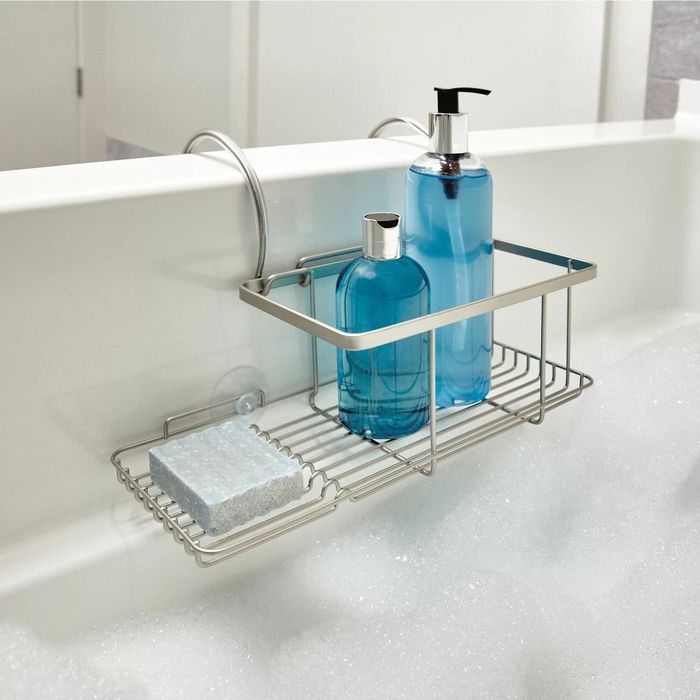 A caddy resting on the ledge of a bathtub, holding two bottles and a sponge, keeping your bath essentials neatly organized.