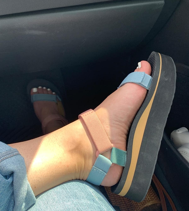 A close-up of light multi-colored Teva sandals worn by a reviewer