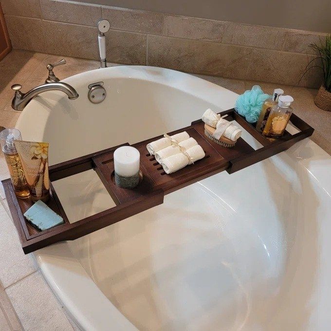 A reviewer’s photo showcasing the bath caddy holding various items over a bathtub, demonstrating its versatility and convenience.