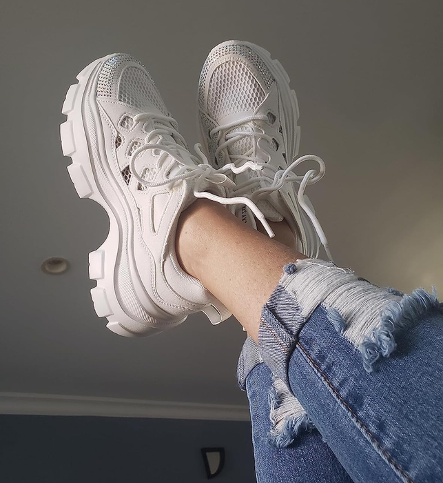 A person rocking chunky white sneakers adorned with rhinestones