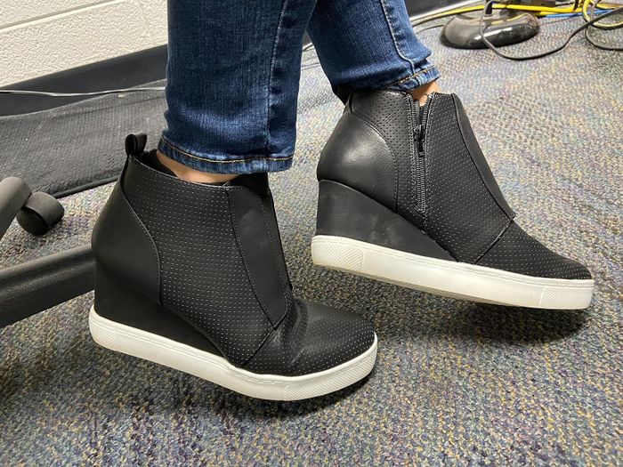 A person sporting black wedge sneakers