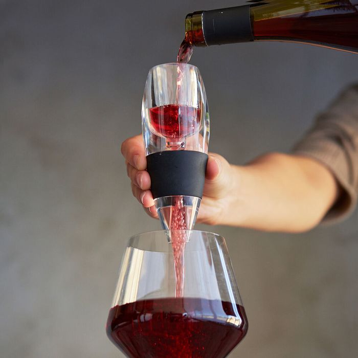 A model elegantly decants red wine using an aerator, filling a glass with precision.