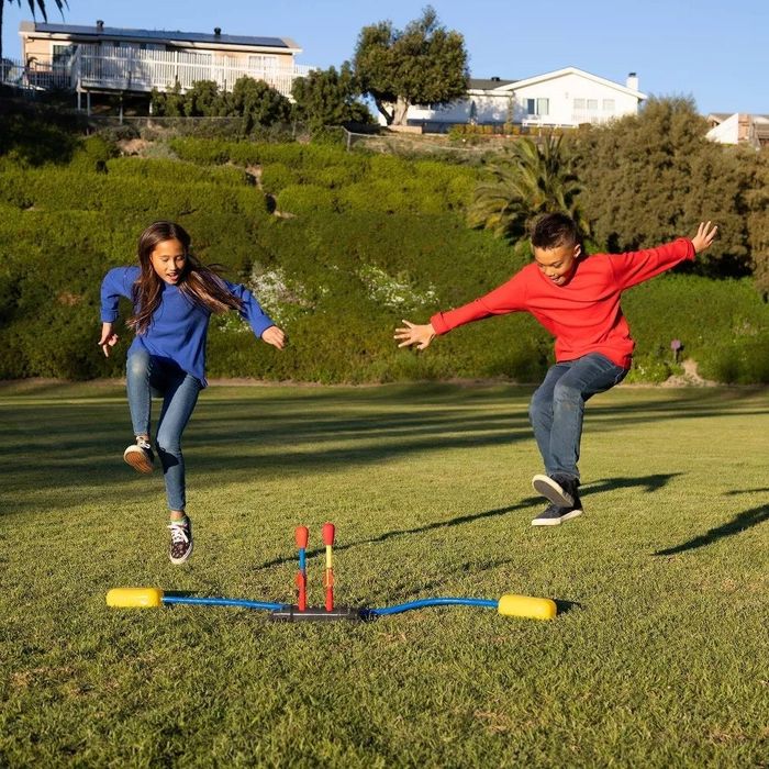 Two children outside, mid-air, just about to launch their rockets into the sky
