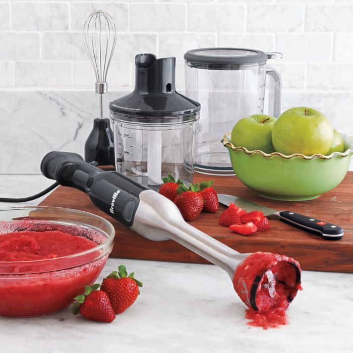 The blender is shown blending fresh strawberries into a smooth mixture.