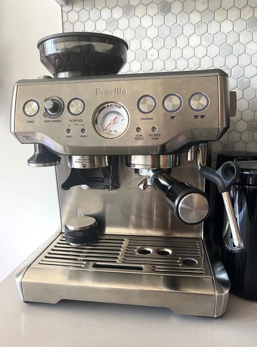 An espresso machine accompanied by a tamper (note: tamper not included).