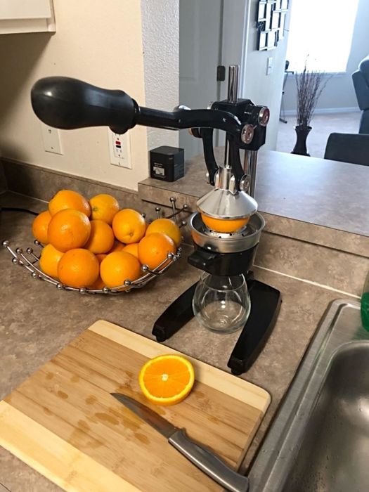 A reviewer's photo demonstrating the use of a squeezer to extract fresh orange juice.