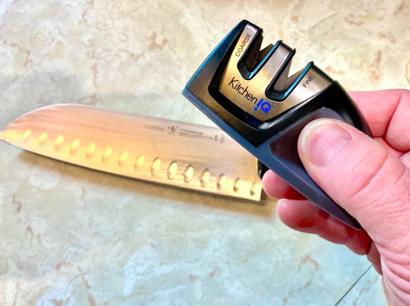 A reviewer's photo displaying the knife sharpener placed beside a kitchen knife.