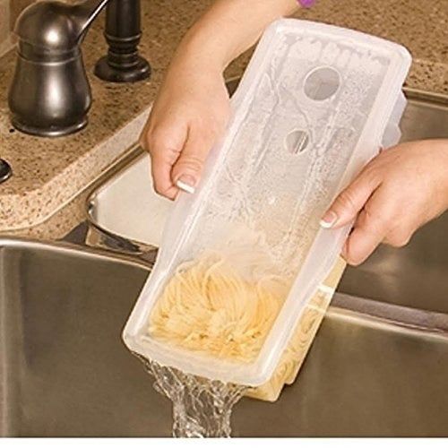 A model's hand is shown holding the pasta cooker, carefully draining water into the sink while the cooked pasta remains inside.