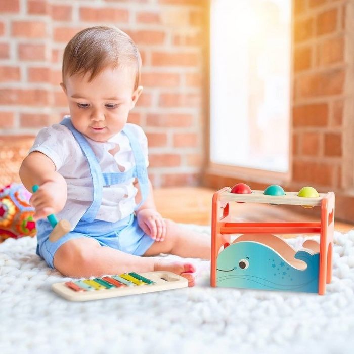 A baby playing with a pounding bench and xylophone