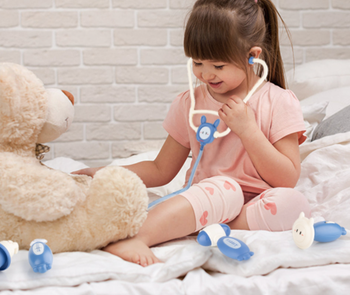A child playing doctor, pretending to check the heartbeat of a stuffed animal.