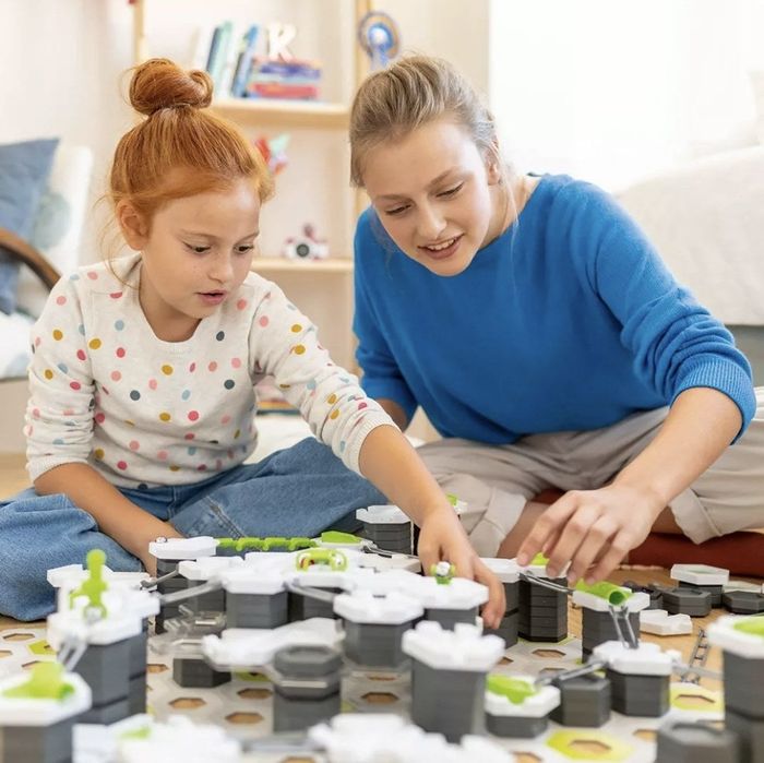A family enjoying quality time together while playing with a marble run.