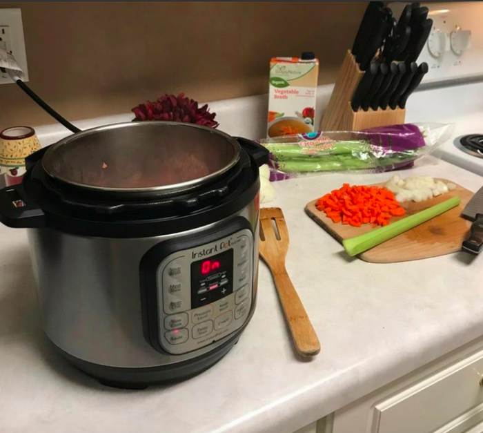 Photo of a reviewer’s Instant Pot on a kitchen counter, accompanied by a cutting board filled with freshly chopped vegetables