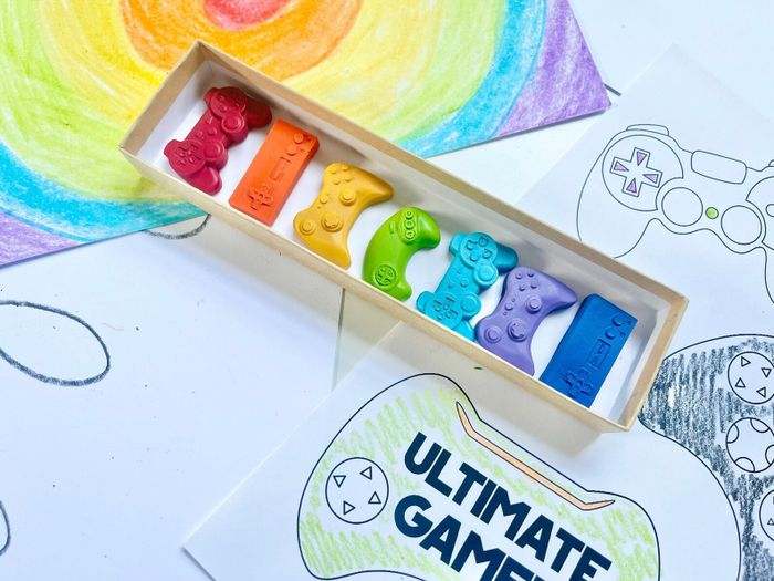 Open packaging showcasing a rainbow array of crayons shaped like popular video game controllers.