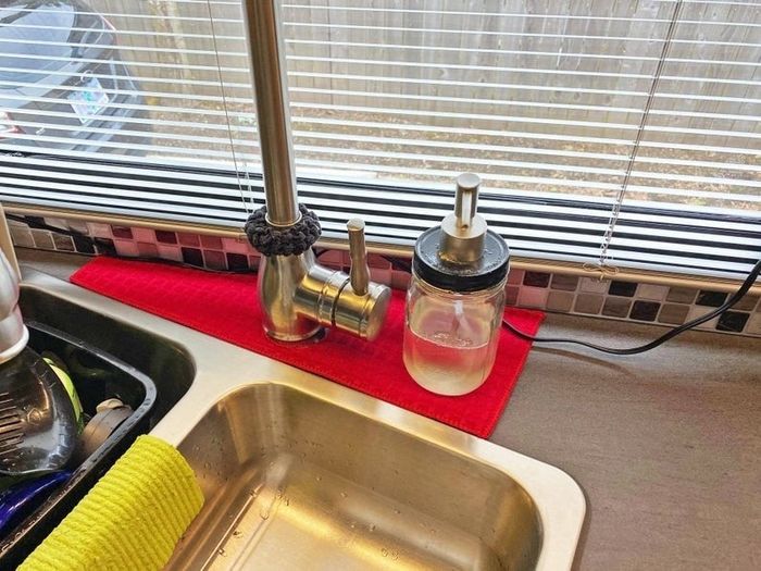 A red drip catcher positioned around the faucet of a kitchen sink.
