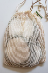 A reviewer's photo showcasing the reusable makeup remover pads inside the provided mesh bag, making washing them effortless.