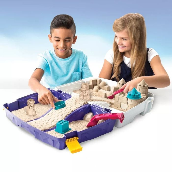 Two child models having fun with an open purple and white sandbox