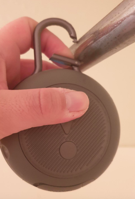 Photo of the speaker securely clipped to a shower rod