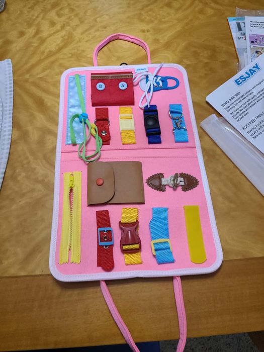 An activity board featuring zippers, buckles, and snap enclosures for hands-on play.