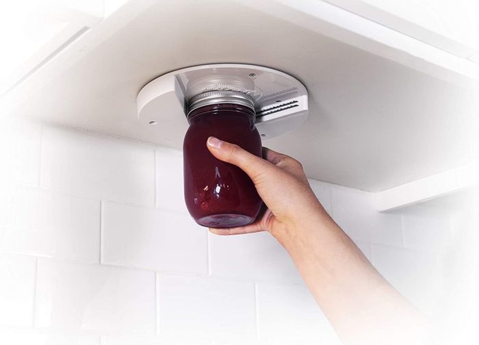 A hand using the gadget to open a mason jar