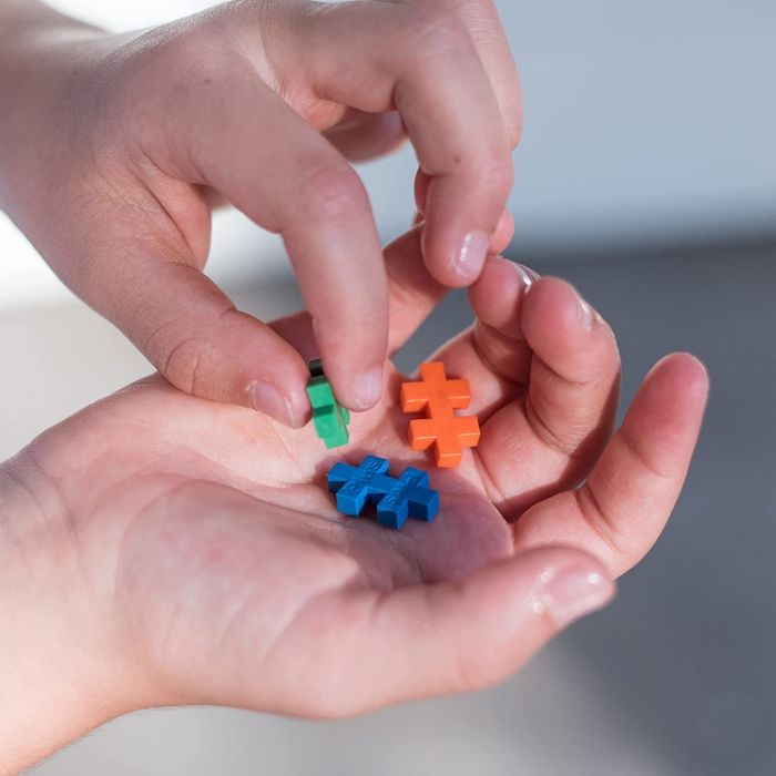 Model holding a colorful assortment of Plus Plus building pieces for scale