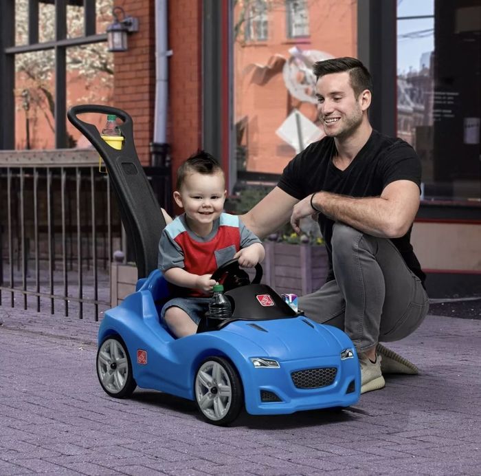 A child happily playing in a push car.