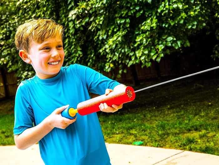 Child model spraying water from a red foam blaster