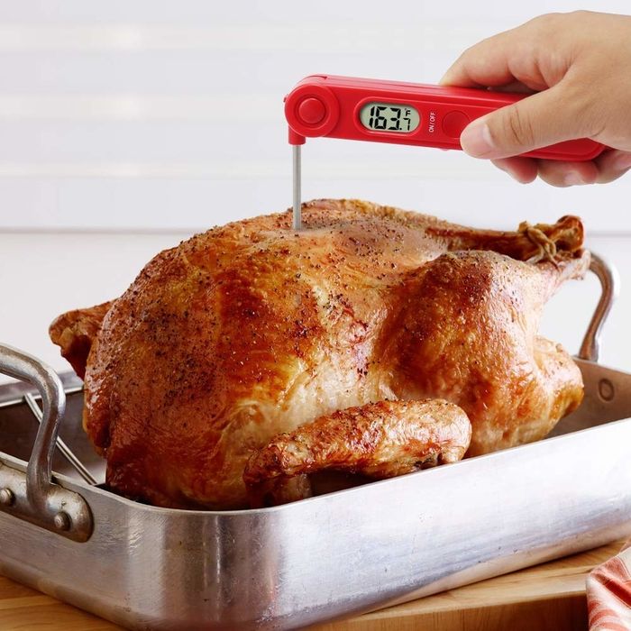 The red thermometer with its stainless steel probe inserted into a roasted turkey