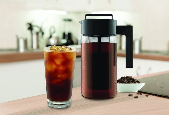 The cold-brew maker placed beside a glass of freshly made cold brew