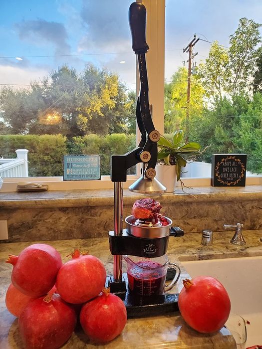 A reviewer's photo of a squeezer being used to prepare pomegranate juice.