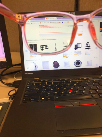 Photo of a reviewer holding blue light glasses in front of a glowing computer screen