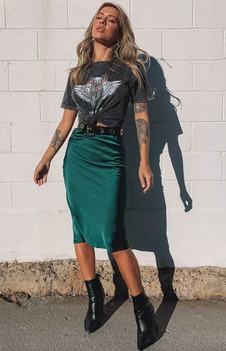 Model is wearing a charcoal grey top and an emerald green midi skirt