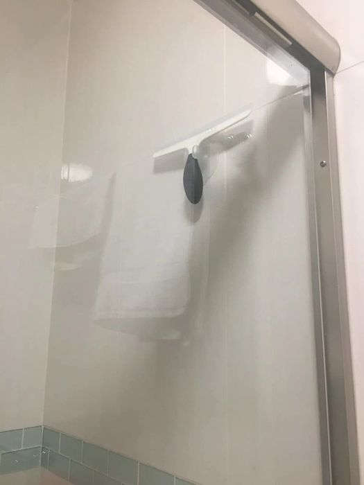 A squeegee hanging on the wall of a shower