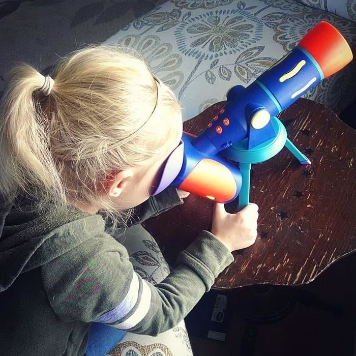 A child engaged with the GeoSafari Jr. telescope, exploring the stars and learning new facts.