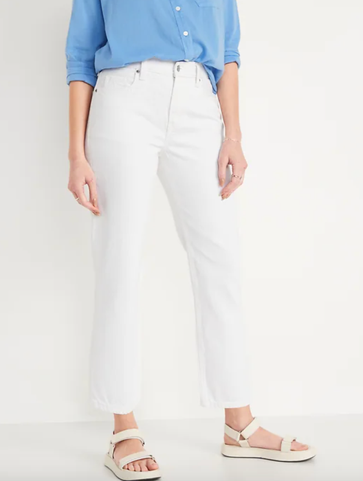 Model is wearing white denim jeans, cream sandals, and a blue button-down shirt.