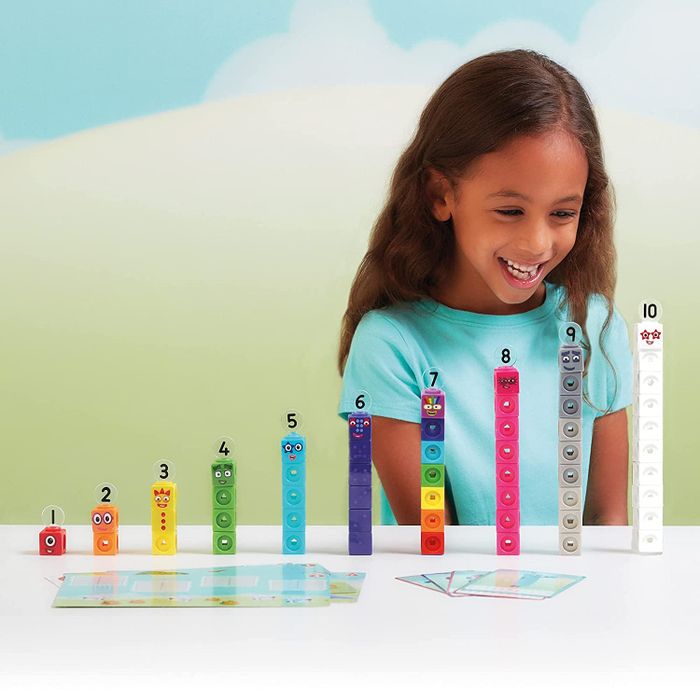 A child playing with stacks of Numberblocks toys, carefully arranging the colorful cubes.