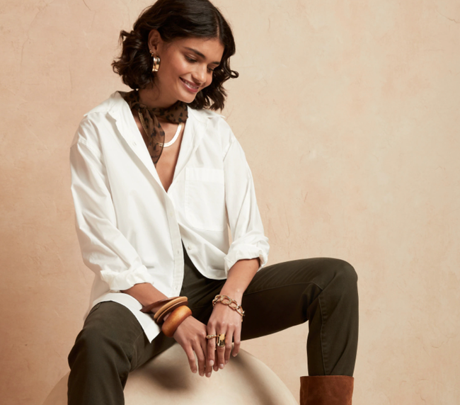 The model is dressed in a white oversized button-down shirt paired with black pants.