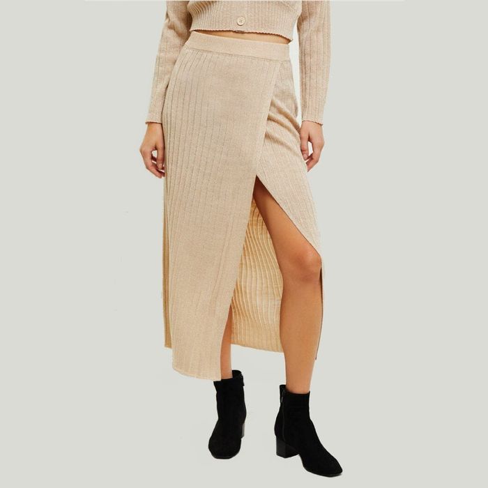 The model is wearing a cream-colored ribbed bodycon midi skirt featuring a front slit.