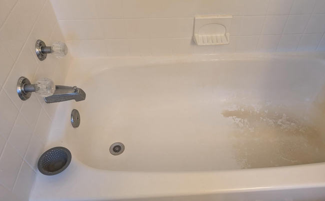 A bathtub with soap scum and a drain cover, highlighting a common cleaning dilemma. Featured in a shopping guide for powerful bathroom cleaning solutions
